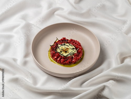 Foto Beef tartare is presented on a round plate
