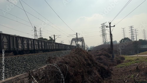 Chengdu, China - March 12 2026: A continuous 4K long shot of a heavy freight train passing over a bridge with authentic rail clatter and locomotive engine sounds.