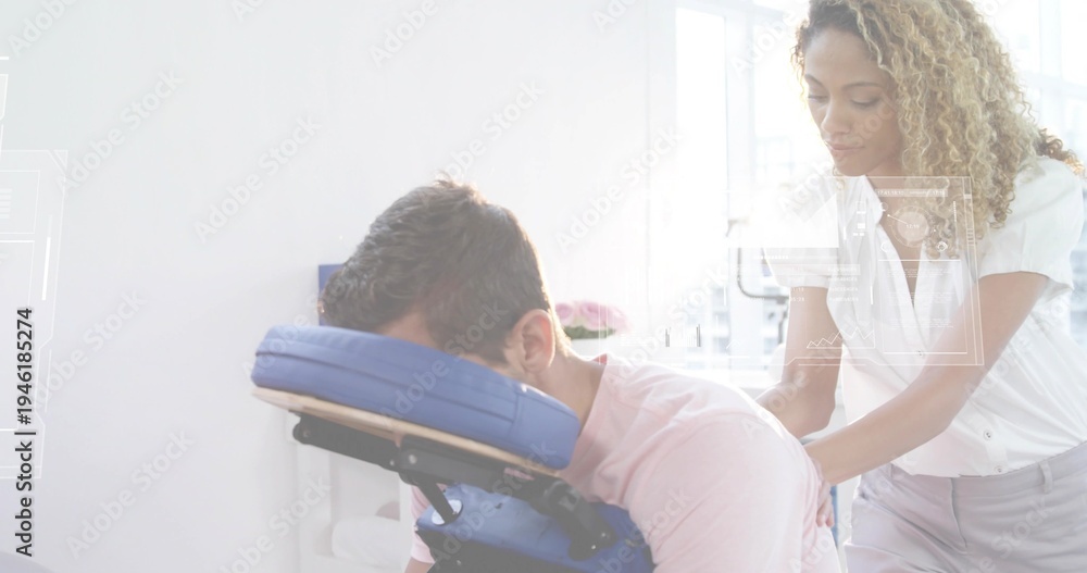Obraz premium Giving therapist in white blouse massaging male client in pink T-shirt in clinic, with blue chair