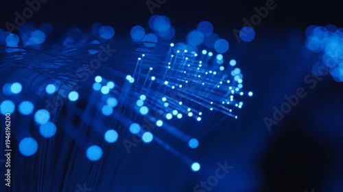 Closeup of glowing blue fiber optic strands in darkness.