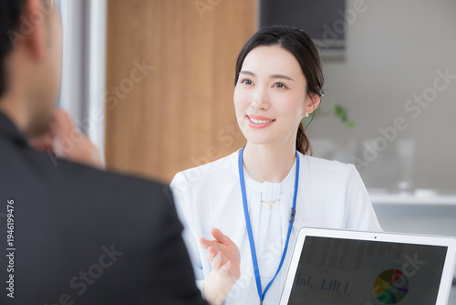 お客様やデスクに座りパソコンのグラフを見ながら保険や投資、nisaや説明のプレゼンやキャリアカウンセリングなどの対面の打ち合わせをする営業女性などの爽やかなイメージ　