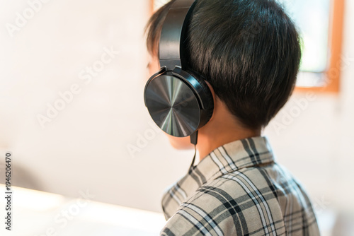 Принти на полотні A child's back view, listening to loud music or playing games with headphones on (headphone-induced hearing loss, hearing impairment)