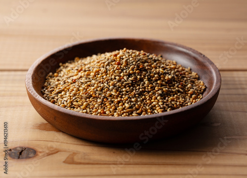 Mixed bird seeds in a wooden bowl on a wooden table