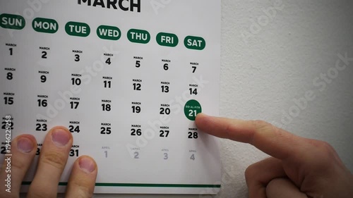 Close-up of a male hand pointing finger at the date of Eid al-Fitr 2026 on a wall calendar