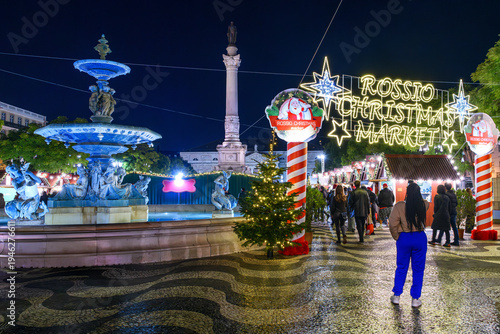 Evening view of holiday decorations and food booths at the public outdoor Rossio Christmas Market in the Baixa district of Lisbon, Portugal.