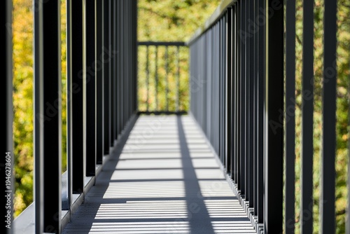 Repeating metal railing creates a pattern of shadows on a walkway