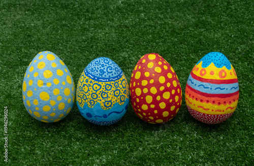 Row of colorful hand-painted Easter eggs on green grass background.