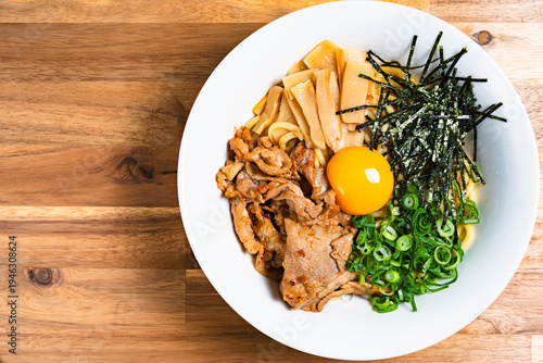 豚肉と生卵をのせた油そば 木製テーブルの上の手作りまぜそば