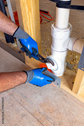 Plumber installing PVC drain pipe and securing plumbing system in new residential construction Florida USA