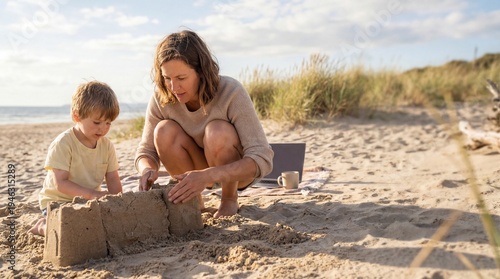 Mother and son building sandcastle on beach during sunny day  