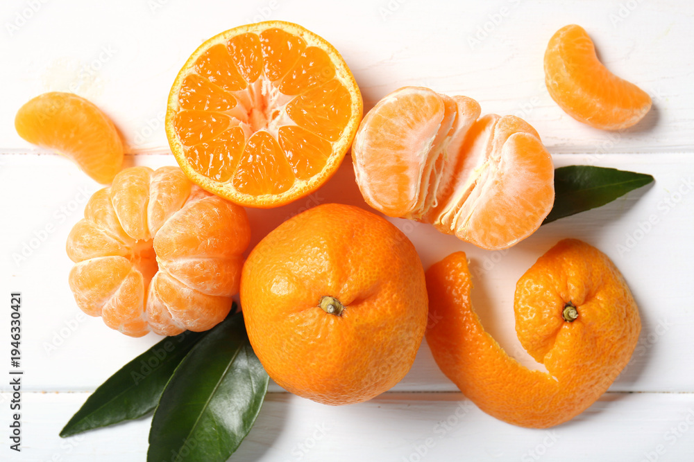 Naklejka premium Sweet mandarins and leaves on white wooden background