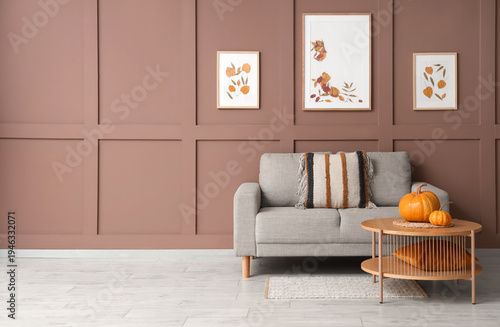Comfortable sofa and table with autumn decor in interior of living room