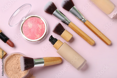 Composition with cosmetic products and makeup brushes on pink background, closeup
