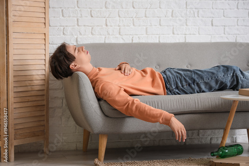 Tablou pe pânză Drunk young man sleeping on sofa at home after party
