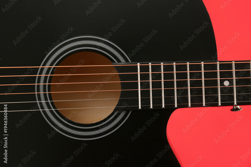 Fototapeta premium Modern black guitar on red background, closeup