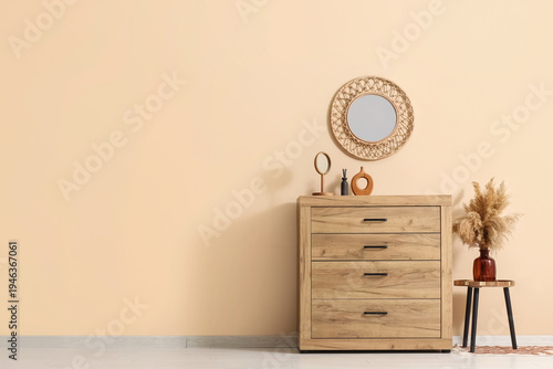 Chest of drawers and round mirror on beige wall in living room