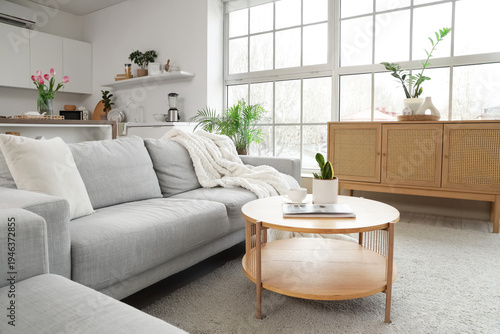 Interior of modern studio apartment with sofa, table and kitchen counters