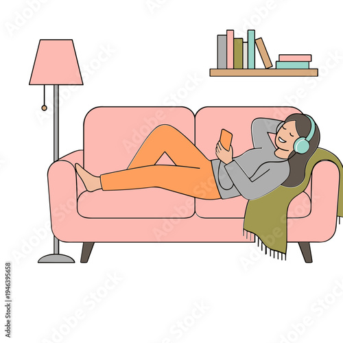 A woman relaxes on a pink couch listening to music with headphones and reading a book.
