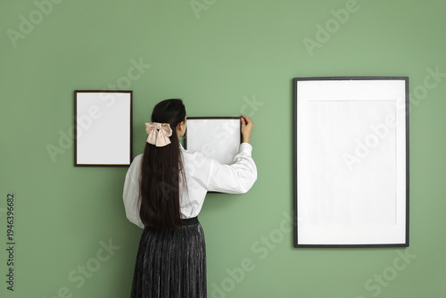 Young woman hanging picture...