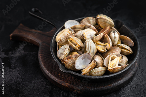 Fotografie Cooked vongole shellfish in black pan on rustic surface