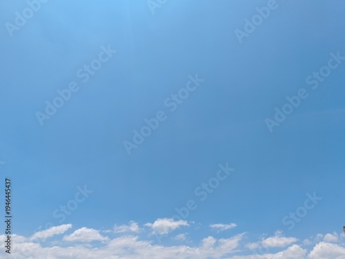Wide expansive blue sky background featuring a thin line of cumulus clouds along the bottom horizon. Great for clean copy space.