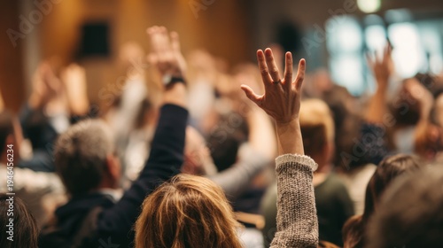 People in an audience raising hands, asking a question, expressing opinion, or showing participation during a business conference
