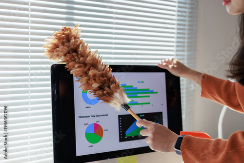 Woman dusting computer monitor with business data charts
