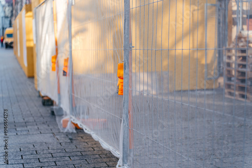 Temporary construction fencing installed along a city sidewalk at an urban building site. Industrial safety and infrastructure development concept highlighting renovation and municipal work in
