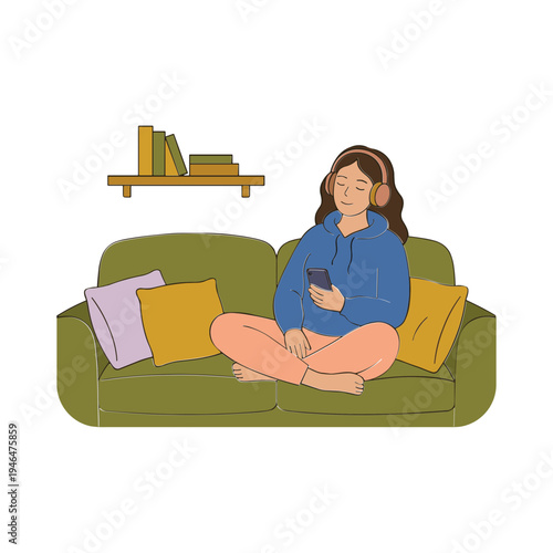 A woman sits on a green couch listening to music on her phone.