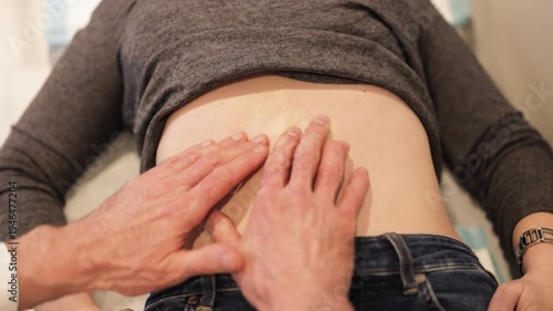 Medical professional performs gentle abdominal palpation on patient for health assessment. Examination focuses on wellness, potentially evoking feelings of comfort, apprehension regarding diagnosis.