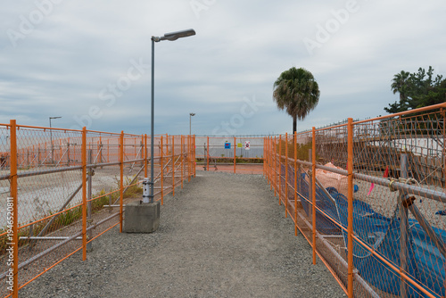 Wallpaper Mural Orange safety fences bordering a gravel path at a construction site under a cloudy sky Torontodigital.ca