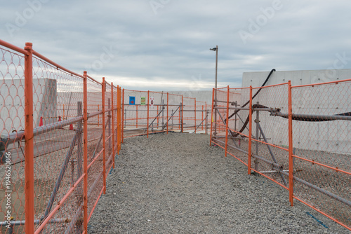 Wallpaper Mural Orange safety fences bordering a gravel path at a construction site under a cloudy sky Torontodigital.ca