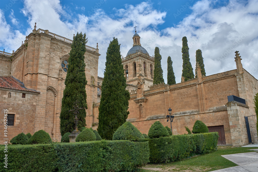 Obraz premium Detailed view of the Romanesque tower of Ciudad Rodrigo Cathedral in Salamanca, with a cloudy sky and green trees in the foreground