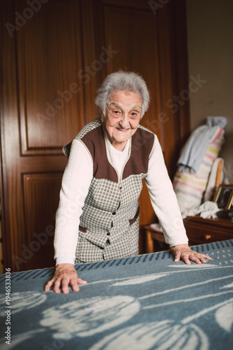Senior woman putting fresh sheets on a bed