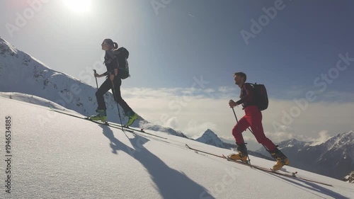 Backcountry Skiers Climbing Snowy Mountain Ridge at Sunrise