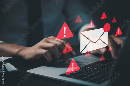 Tableau sur toile A businessman typing on a laptop with warning email icons, illustrating email th
