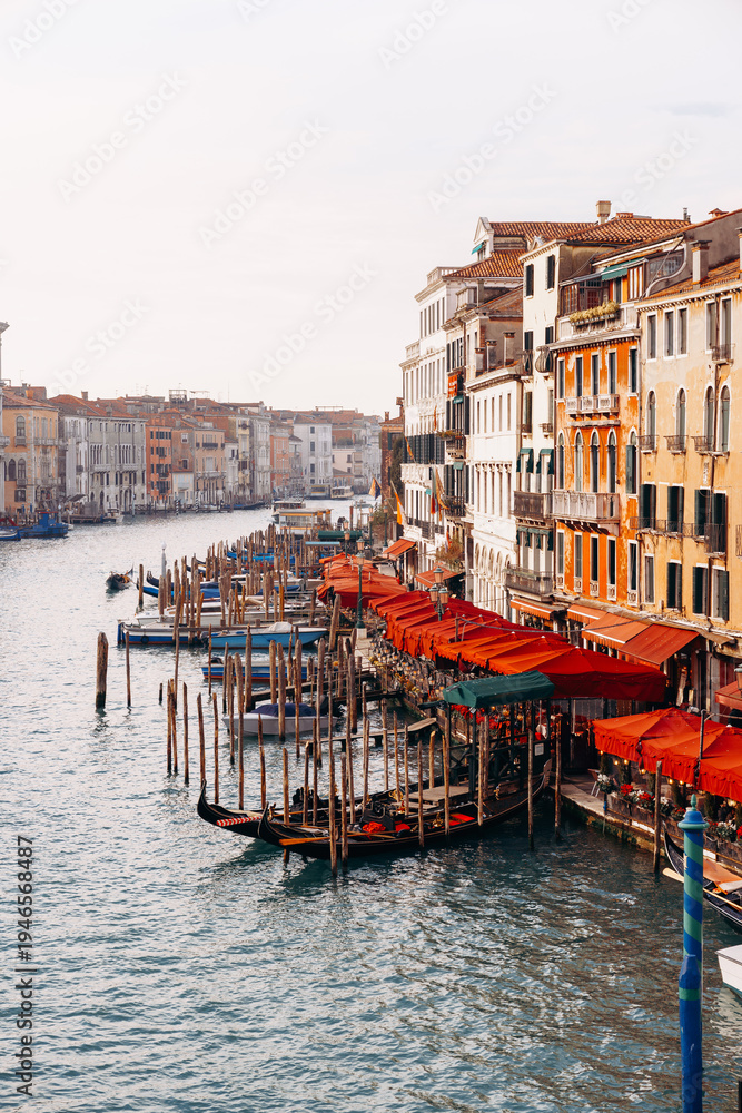 Fototapeta premium Gondolas float in the canal near restaurants and buildings in Venice during the late afternoon