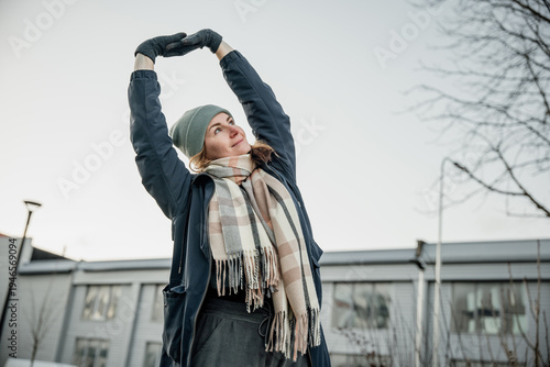Bild auf Leinwand Young person stretches in cold weather outside a building during daytime in wint