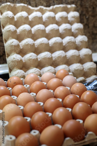 large tray of fresh brown chicken eggs in cardboard carton on kitchen countertop, organic food ingredient for cooking, baking and breakfast preparation in home kitchen