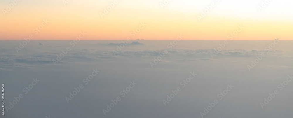 Naklejka premium Sunrise or sunset sky from an airplane window, view of clouds from above