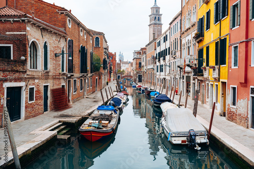Tableau sur toile Quiet canal in Venice with boats and colorful buildings in the background near e