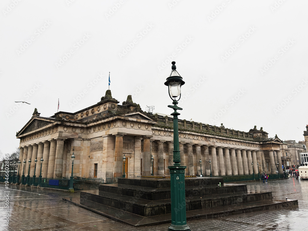 Fototapeta premium Neoclassical municipal National Gallery building with columns and lamppost on wet plaza in Edinburgh, Scotland, UK, historic architecture and urban landmark in overcast weather