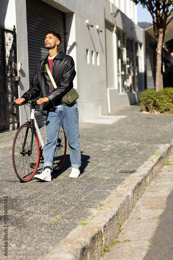 Fototapeta premium Man in twenties walking road bike with red rim on sidewalk by storefront, holding olive bag