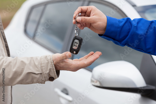 Bilde på lerret Close-up of a professional mechanic or dealer handing over car keys to a customer in front of a white vehicle