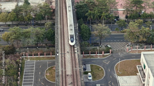 High-speed passenger train moving tracks next to construction site. Modern transportation, urban expansion. City railway system. Rail way road. Aerial top drone view. Fast express commuter railroad.