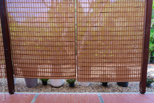 Brown bamboo curtain outdoor privacy screen garden decoration potted plants gravel ground wooden frame natural light patio flooring peaceful