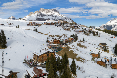 Φωτογραφία Aerial winter panorama of Lech and Oberlech in the Austrian Alps shows skiers, lifts, timber and glass lodges, a steaming infinity pool, and the Arlberg massif in crisp daylight
