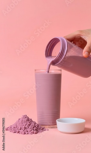 Mixing a protein beverage, pouring a pink strawberry shake into a glass to represent a food supplement idea