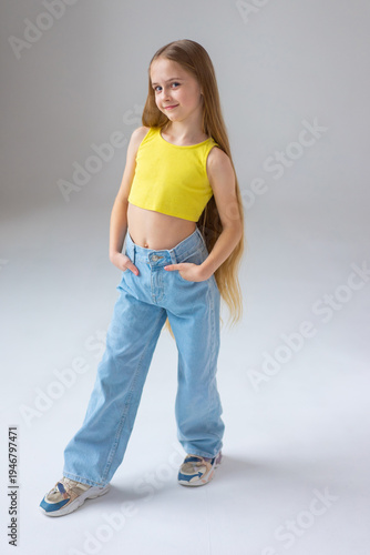 Happy little girl model with long blondie hair. Emotional, cheerful, joyful, cute, adorable caucasin girl posing in studio