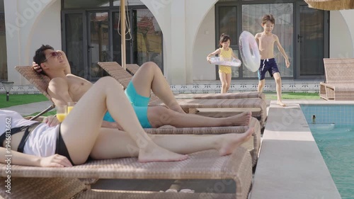 A young family relaxes poolside, enjoying their getaway